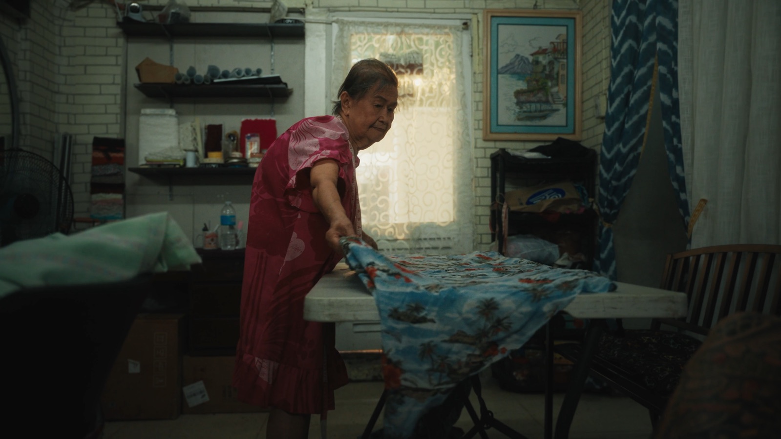 Lola ironing fabric by the window in her home in the Philippines